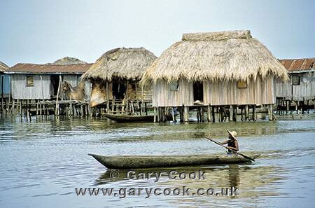 Local woman paddling her pirogue through Granvie stilt village, Benin