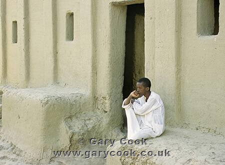 Young Bozo man sitting on the steps of the mosque, Mali
