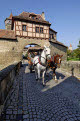 Tourist horse and carriage passing through the Rodertor (Roder Gate), gate in the city walls, Rothenburg ob der Tauber, Bavaria, Germany