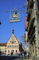 Ornate wrought iron shop sign with the Ratstrinkstube (City Councilors Tavern) in the background, Marktplatz, Rothenburg ob der Tauber, Bavaria, Germany