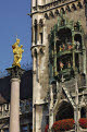 Statue of the Virgin Mary with the glockenspiel figures on the tower of the Neues Rathaus (New Town Hall) in the background, Marienplatz, Munich, Bavaria, Germany